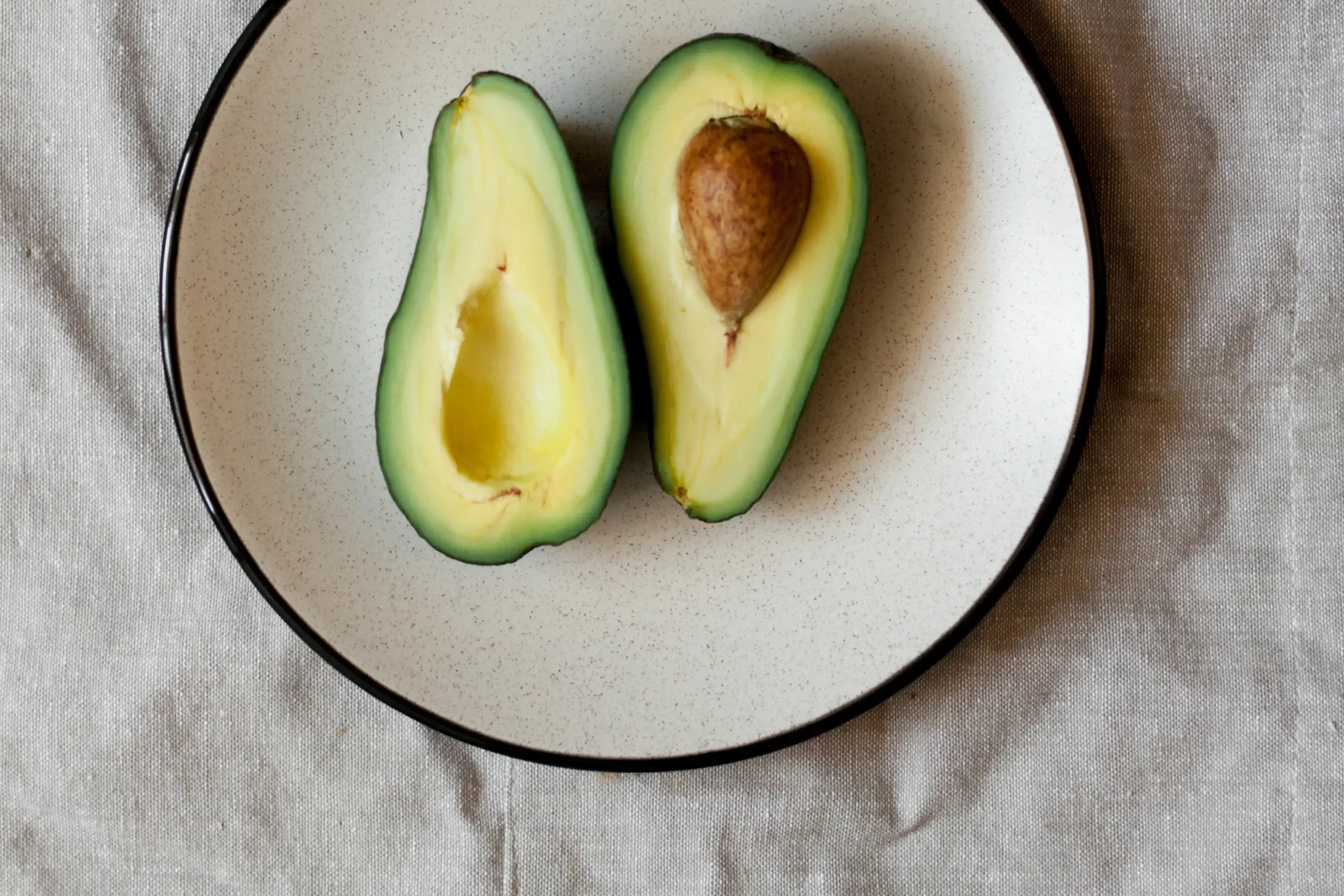 avocado cut in half on a cream plate